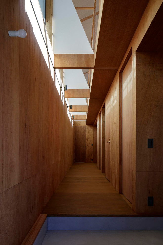 Ejemplo de hall moderno pequeño con paredes marrones, suelo de contrachapado, puerta de madera en tonos medios, suelo marrón, madera, madera y puerta simple