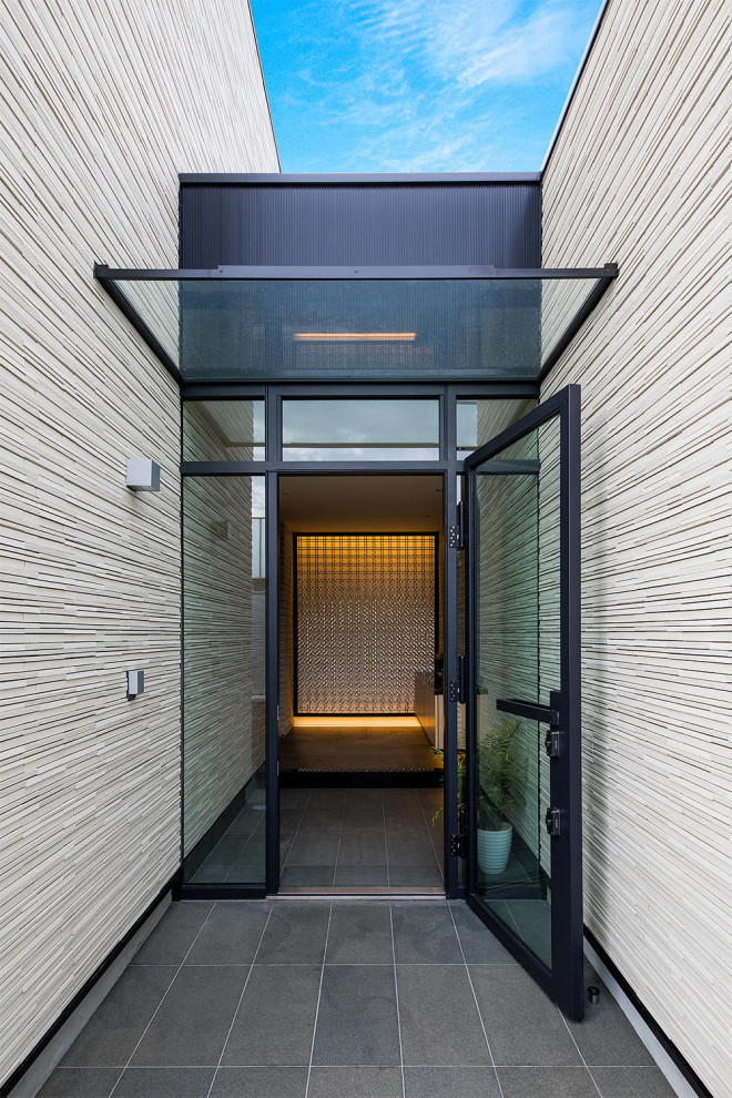 Immagine di una porta d'ingresso minimal con pareti beige, una porta in vetro e pavimento grigio
