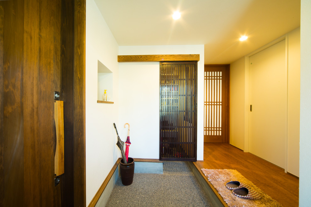 京都にある和風のおしゃれな玄関 (白い壁、無垢フローリング、濃色木目調のドア、茶色い床) の写真