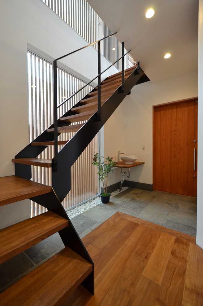 This is an example of a world-inspired hallway in Other with white walls, a single front door, a medium wood front door, grey floors and feature lighting.