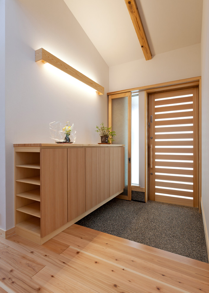 Diseño de hall asiático pequeño con paredes blancas, suelo de madera clara, puerta de madera clara, suelo beige y puerta simple