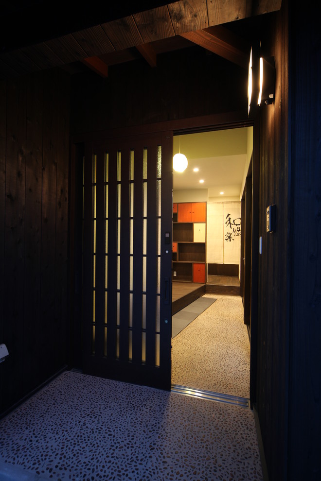 Imagen de puerta principal de estilo zen de tamaño medio con paredes marrones, puerta corredera, puerta de madera oscura y suelo gris