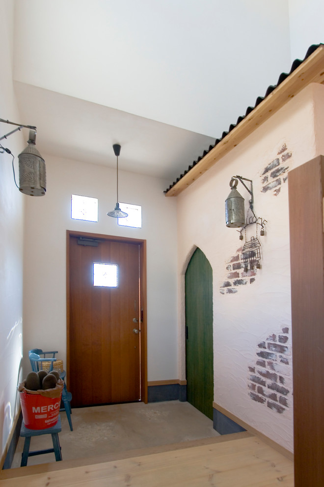 他の地域にある和風のおしゃれな玄関ホール (白い壁、コンクリートの床、木目調のドア、グレーの床) の写真
