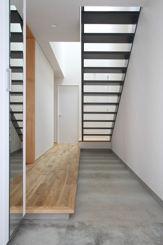 Foto di un corridoio minimalista con pareti bianche, pavimento in cemento, una porta singola, una porta marrone e pavimento grigio