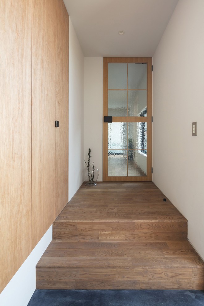 Mittelgroßer Asiatischer Eingang mit Korridor, weißer Wandfarbe, braunem Holzboden, Einzeltür, hellbrauner Holzhaustür und braunem Boden in Osaka