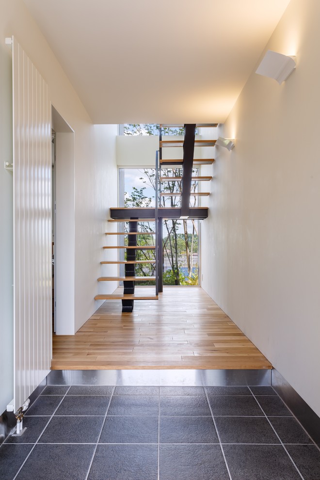 Источник вдохновения для домашнего уюта: узкая прихожая в стиле модернизм с белыми стенами и серым полом