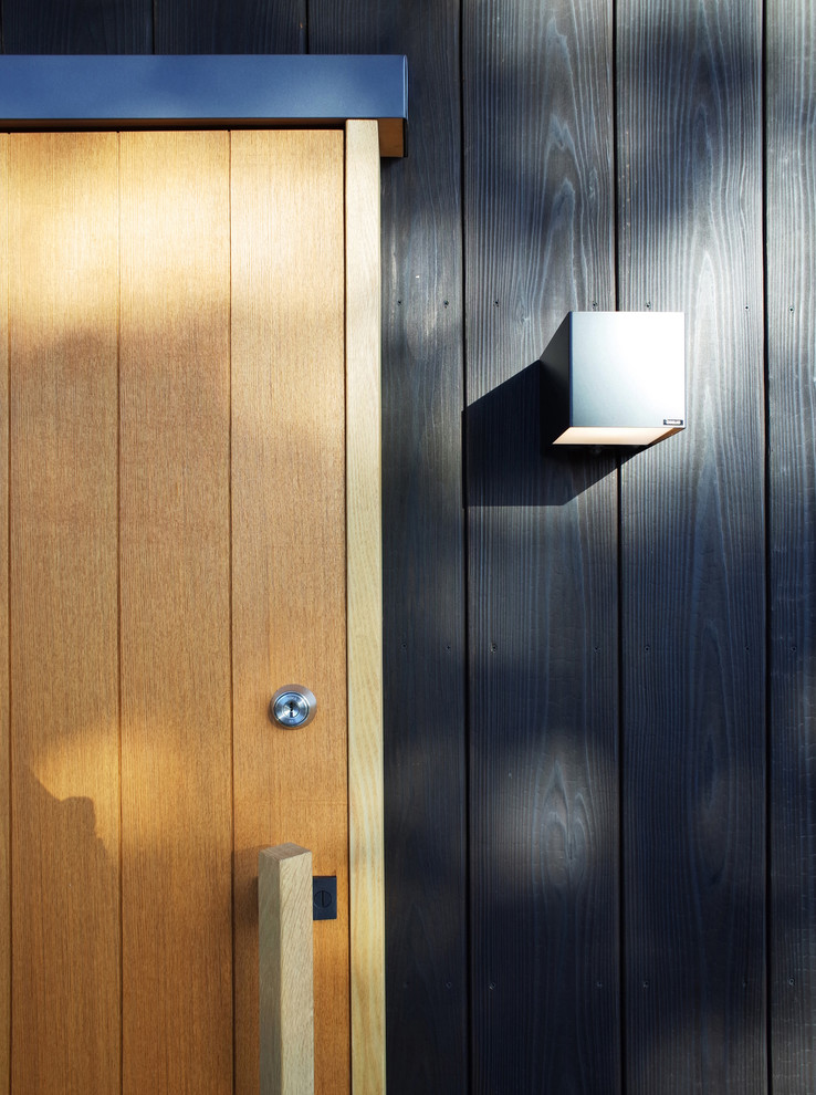 Стильный дизайн: входная дверь среднего размера в скандинавском стиле с черными стенами, бетонным полом, раздвижной входной дверью, входной дверью из дерева среднего тона и серым полом - последний тренд