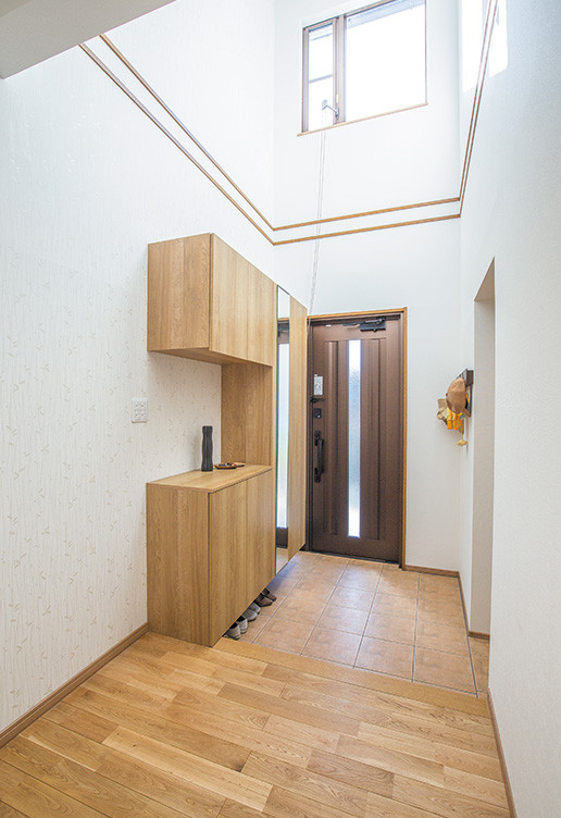 Imagen de hall contemporáneo con paredes blancas, suelo de madera en tonos medios, puerta simple, puerta de madera en tonos medios, suelo marrón, papel pintado y papel pintado