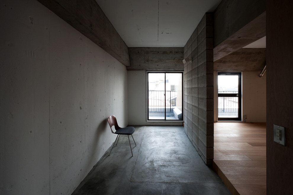 Immagine di un corridoio nordico di medie dimensioni con pareti bianche, pavimento in cemento, una porta singola, una porta grigia e pavimento grigio