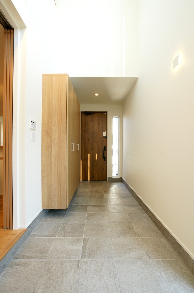 Cette photo montre une entrée moderne de taille moyenne avec un mur blanc, parquet clair et un sol beige.