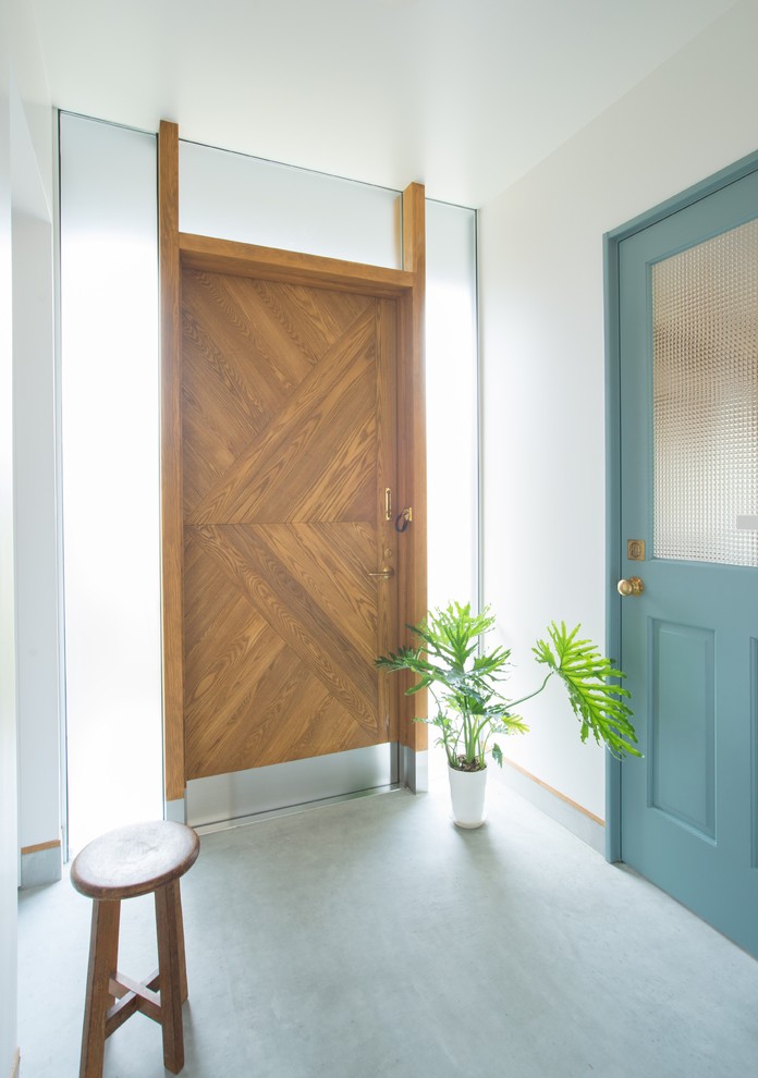Пример оригинального дизайна: узкая прихожая среднего размера в стиле шебби-шик с белыми стенами, бетонным полом, одностворчатой входной дверью, входной дверью из дерева среднего тона и серым полом