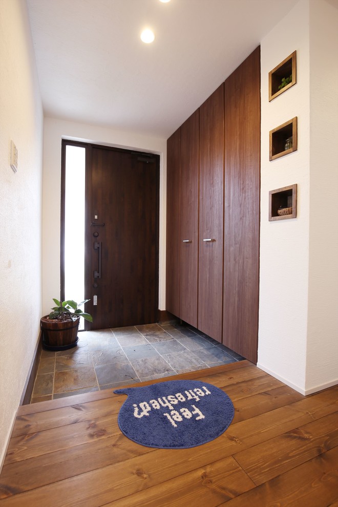 Inspiration pour une entrée asiatique avec un couloir, un mur blanc, une porte simple, une porte en bois foncé et un sol gris.