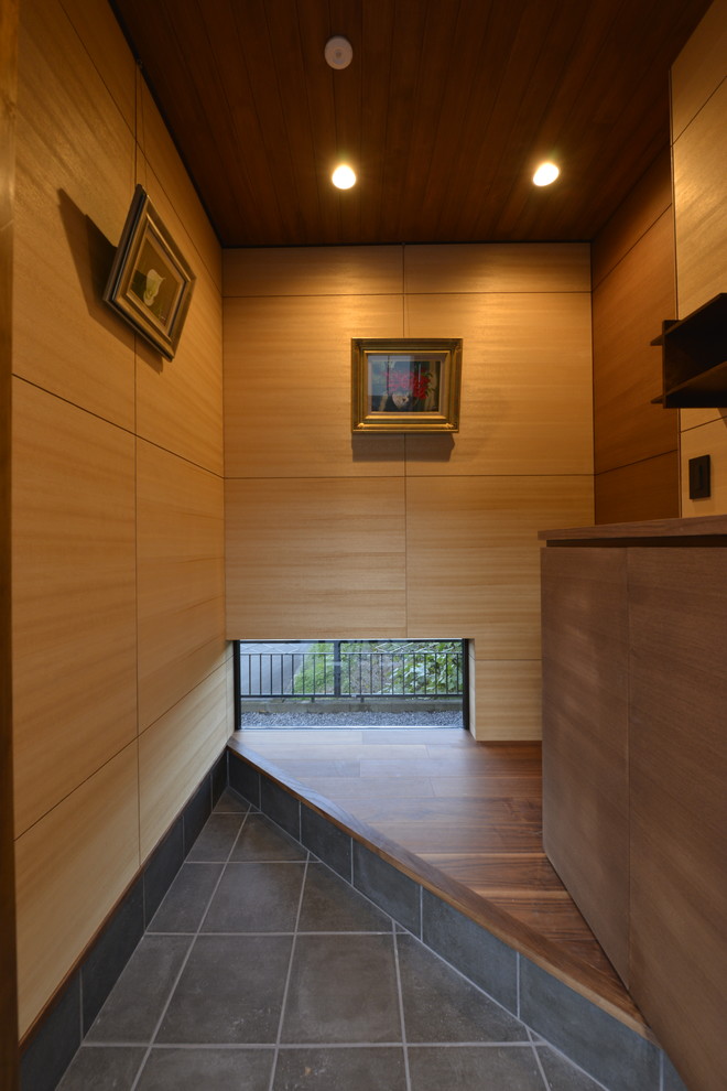 Exempel på en asiatisk entré, med bruna väggar och svart golv