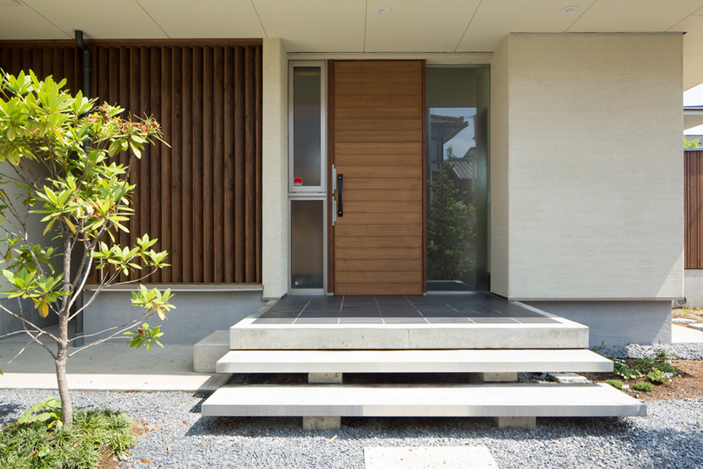 Modelo de entrada campestre de tamaño medio con paredes blancas, suelo de baldosas de porcelana, puerta simple, puerta de madera en tonos medios y suelo negro