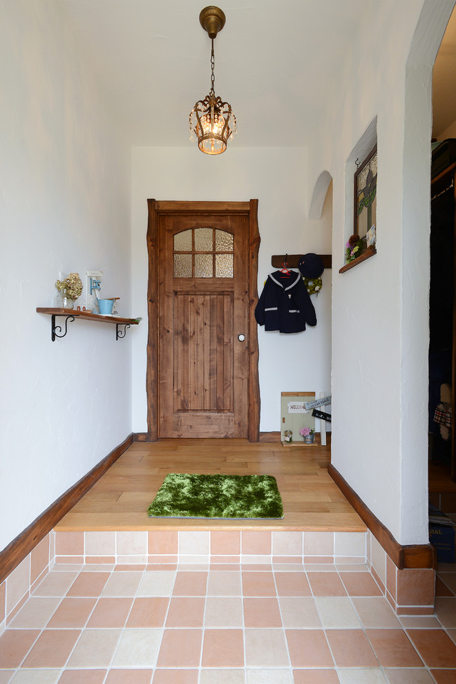Источник вдохновения для домашнего уюта: узкая прихожая в средиземноморском стиле с белыми стенами, одностворчатой входной дверью, входной дверью из темного дерева и оранжевым полом