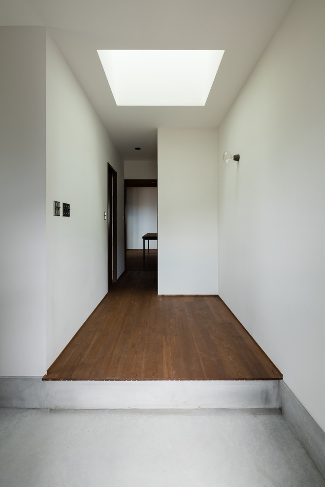 Ejemplo de entrada rústica con suelo de cemento, puerta simple, puerta de madera oscura y paredes blancas