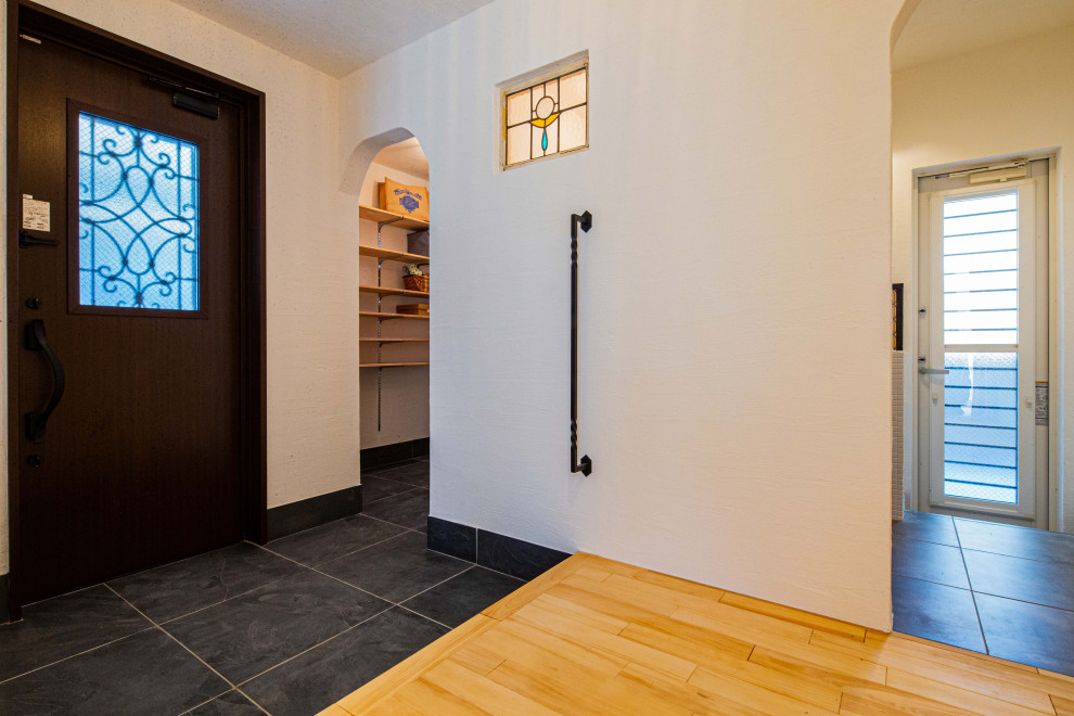 Esempio di un corridoio stile americano di medie dimensioni con pareti bianche, pavimento in ardesia, una porta singola, una porta in legno scuro e pavimento grigio