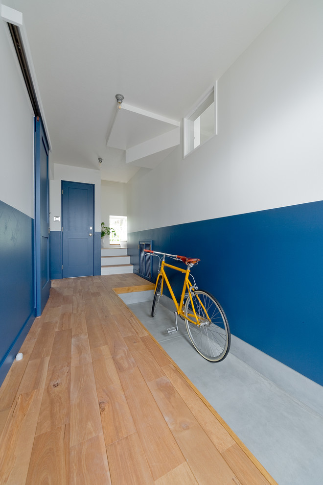 Réalisation d'une entrée craftsman avec un couloir, un mur bleu, parquet clair, une porte simple et une porte blanche.