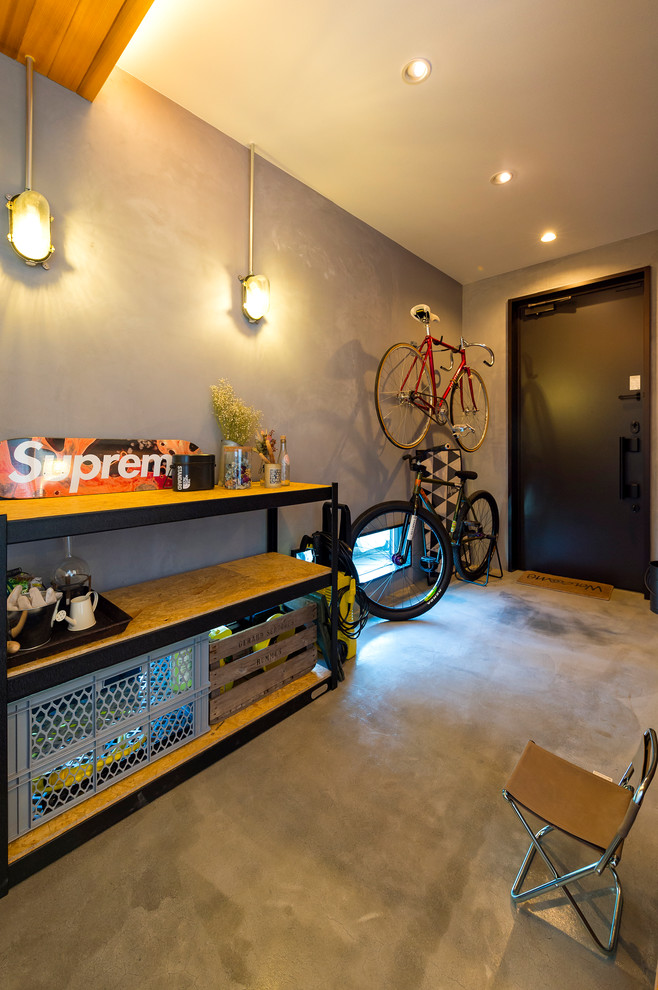 Example of an urban concrete floor and gray floor entryway design in Other with gray walls and a black front door
