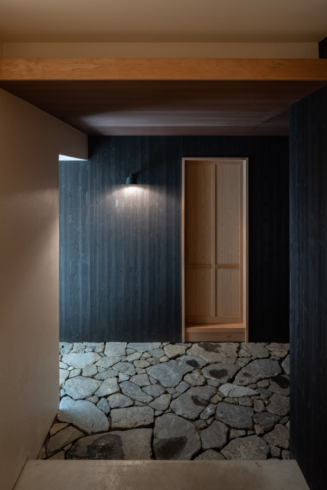 Aménagement d'une petite entrée en bois avec un couloir, un mur noir, une porte simple et un plafond en lambris de bois.