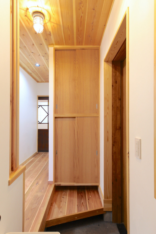 他の地域にあるトランジショナルスタイルのおしゃれな玄関 (白い壁、無垢フローリング、木目調のドア、ベージュの床) の写真
