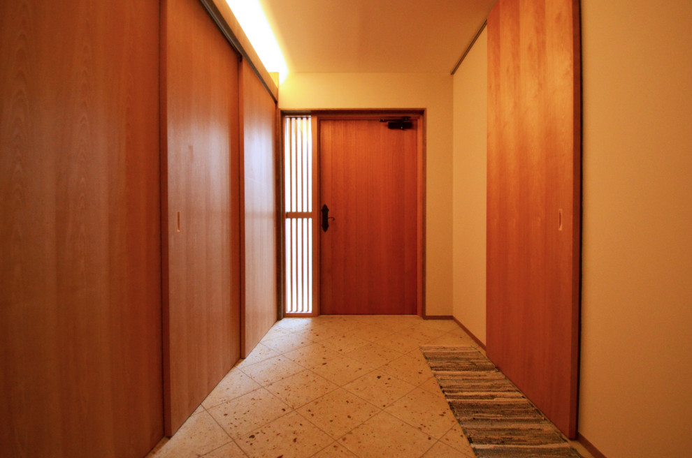 На фото: узкая прихожая среднего размера в скандинавском стиле с бежевыми стенами, полом из известняка, одностворчатой входной дверью, коричневой входной дверью, коричневым полом и потолком из вагонки
