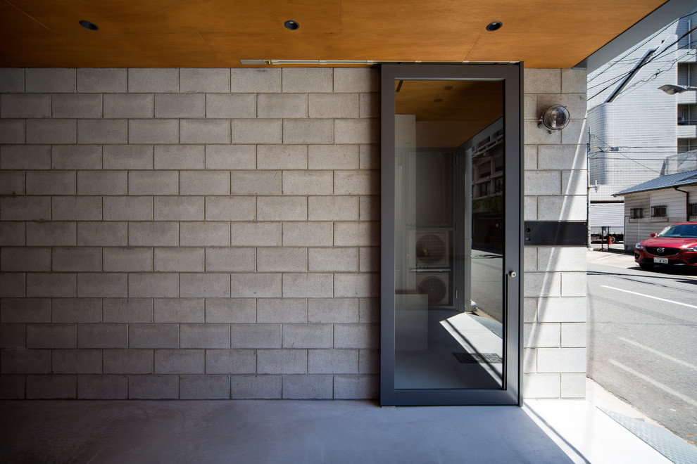 Idées déco pour une petite entrée industrielle avec un couloir, un mur gris, sol en béton ciré, une porte coulissante, une porte grise et un sol gris.