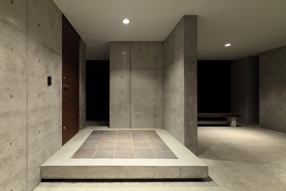 Esempio di una porta d'ingresso design di medie dimensioni con pareti grigie, pavimento in cemento, una porta singola, una porta marrone e pavimento grigio