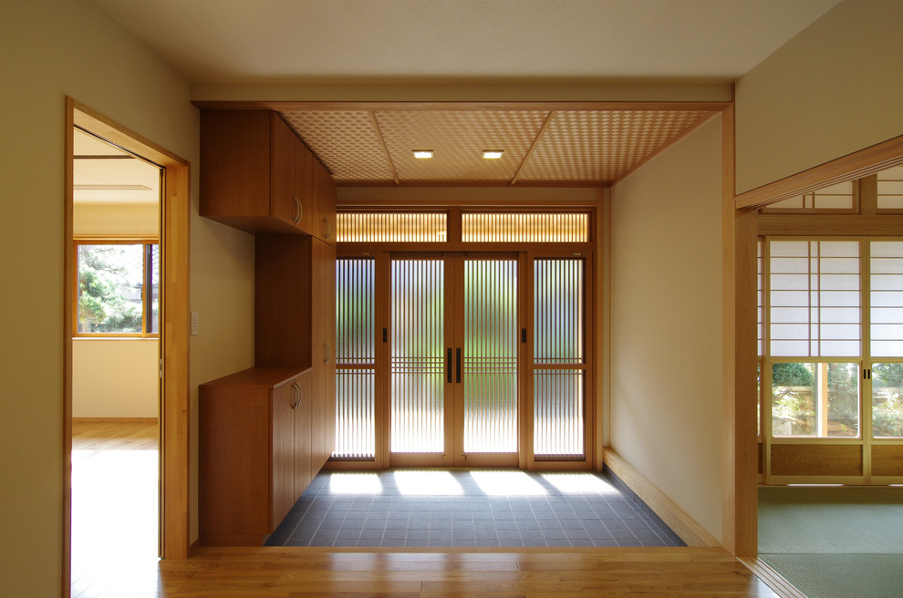 Asiatischer Eingang mit weißer Wandfarbe, hellem Holzboden, Schiebetür, hellbrauner Holzhaustür und Korridor in Sonstige