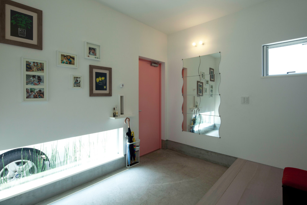 Imagen de hall minimalista de tamaño medio con paredes grises, suelo de cemento, puerta simple, puerta roja y suelo gris