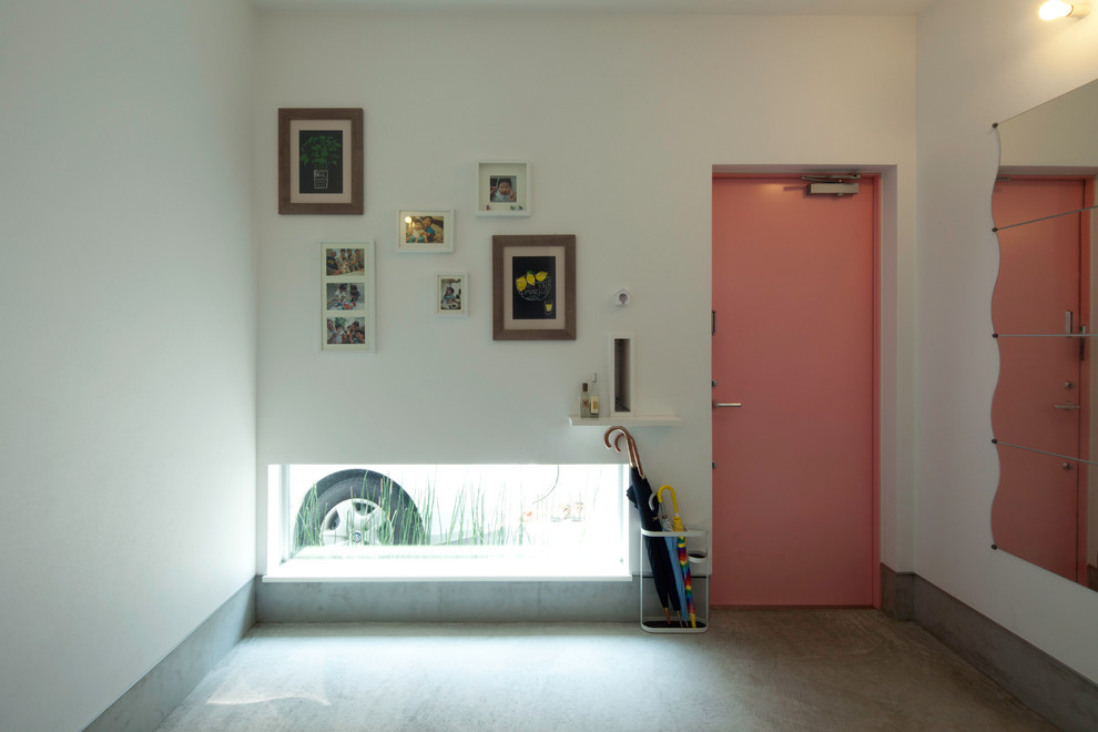 Ispirazione per un corridoio moderno di medie dimensioni con pareti grigie, pavimento in cemento, una porta singola, una porta rossa e pavimento grigio