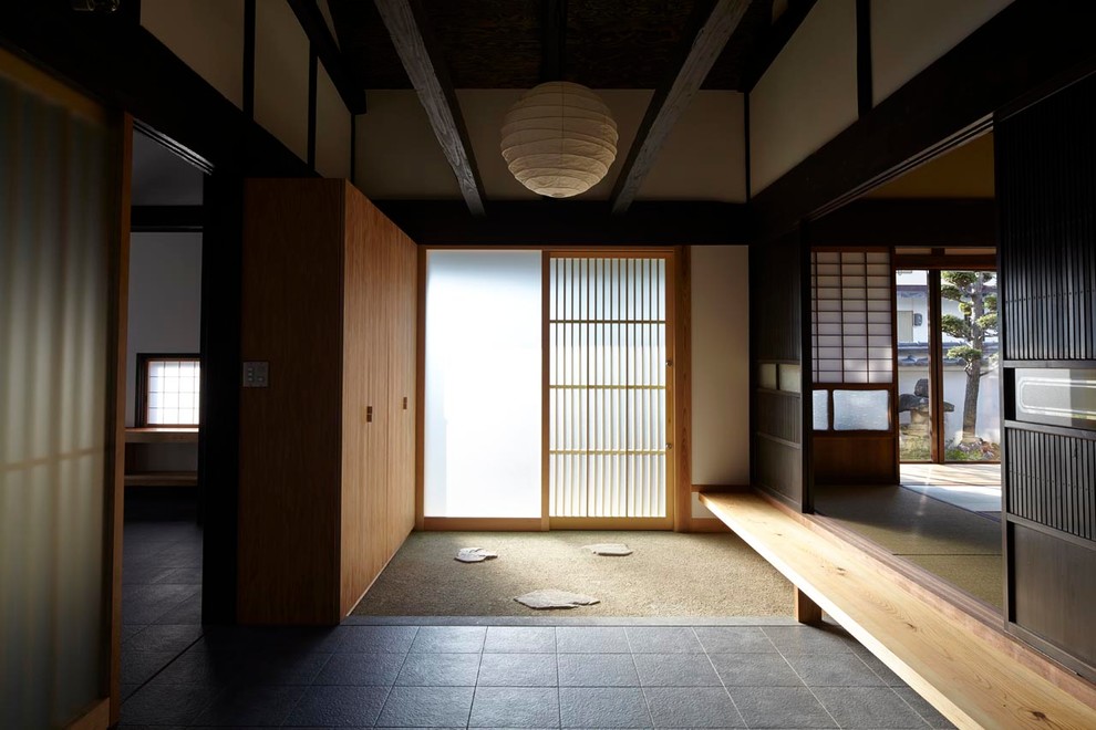 Modelo de entrada de estilo zen con puerta corredera y puerta de madera clara