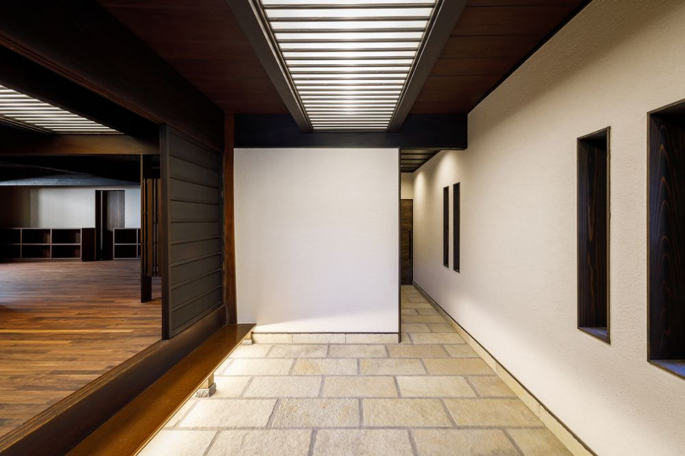 Inspiration pour une grande entrée traditionnelle avec un couloir, un mur blanc, sol en granite, une porte coulissante, une porte en bois foncé et un sol beige.