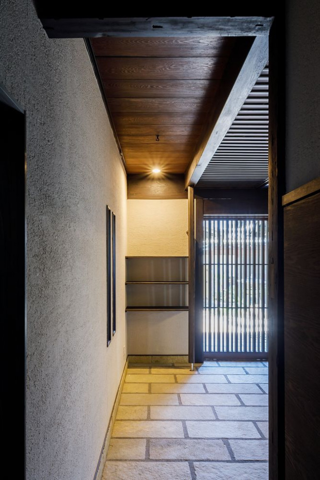広いトラディショナルスタイルのおしゃれな玄関 (白い壁、御影石の床、茶色いドア、ベージュの床) の写真