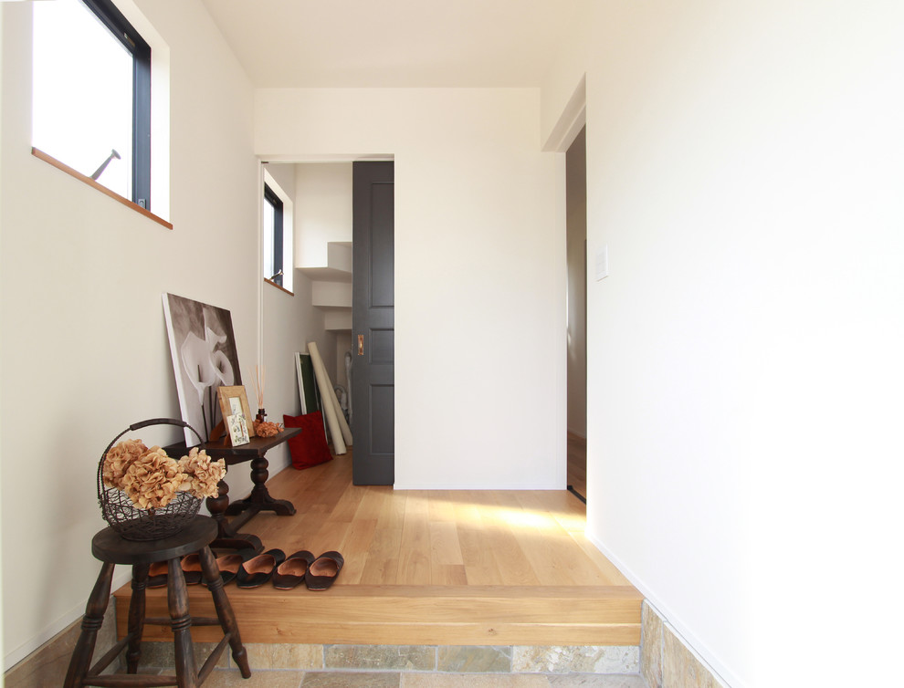 Diseño de hall nórdico con paredes blancas, suelo de madera clara y suelo marrón