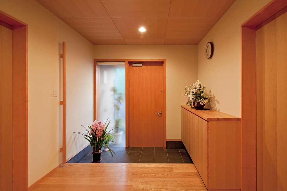 Immagine di un corridoio etnico con pareti bianche, una porta singola, una porta in legno bruno e pavimento nero