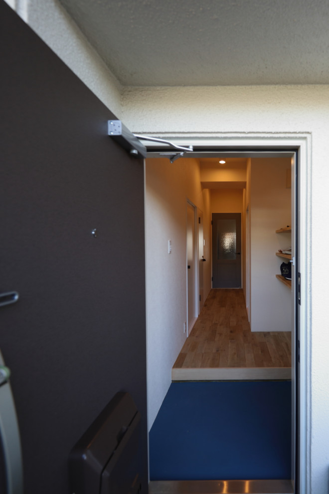 This is an example of a scandi entrance in Osaka with white walls and medium hardwood flooring.