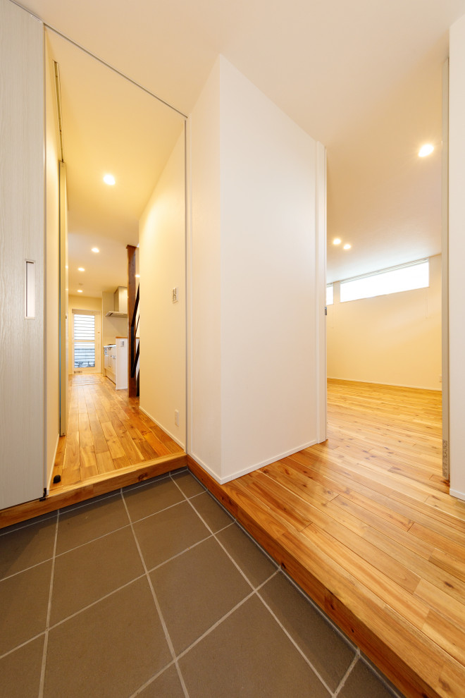 Imagen de vestíbulo posterior minimalista de tamaño medio con paredes blancas, suelo de madera en tonos medios, suelo marrón, papel pintado y papel pintado