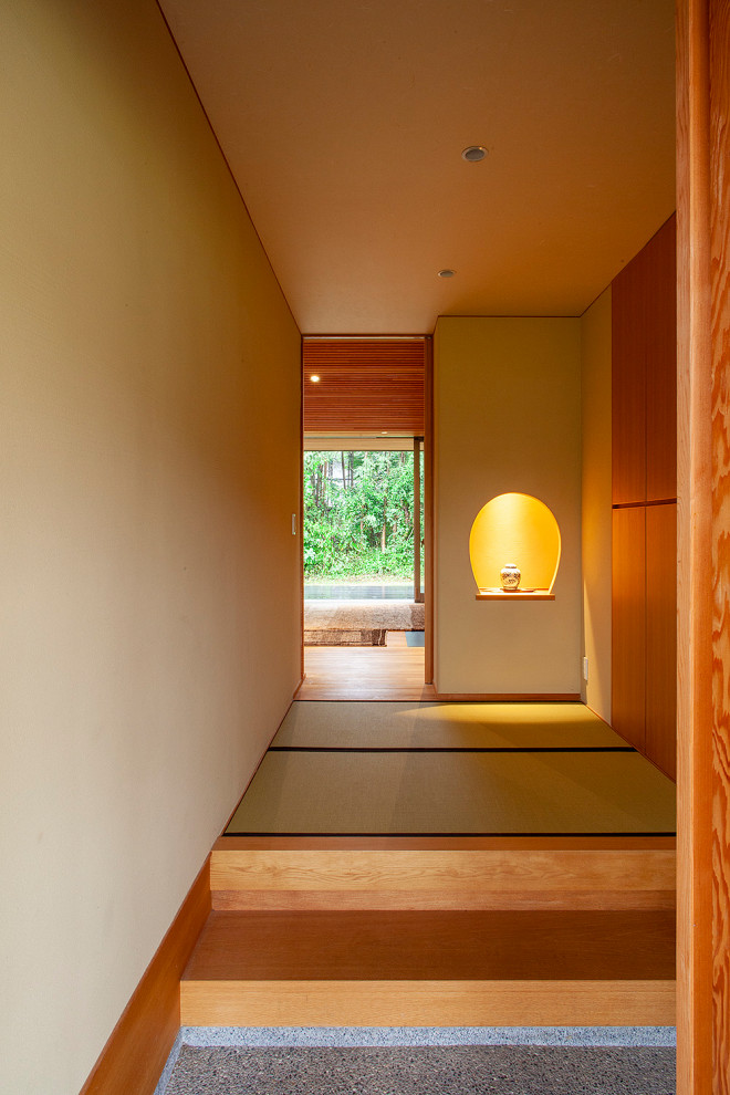 Foto på en mellanstor orientalisk hall, med vita väggar, tatamigolv, en enkeldörr, mörk trädörr och beiget golv
