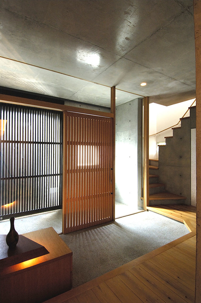 Immagine di un corridoio minimal con pareti grigie, una porta in legno bruno e pavimento grigio