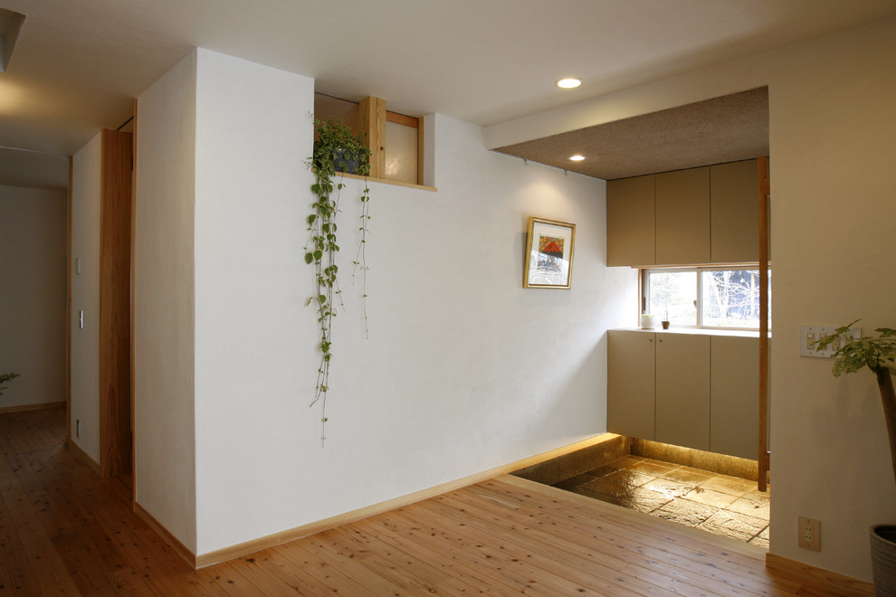 Imagen de hall minimalista de tamaño medio con paredes blancas, suelo de madera en tonos medios, puerta corredera, puerta marrón y suelo marrón
