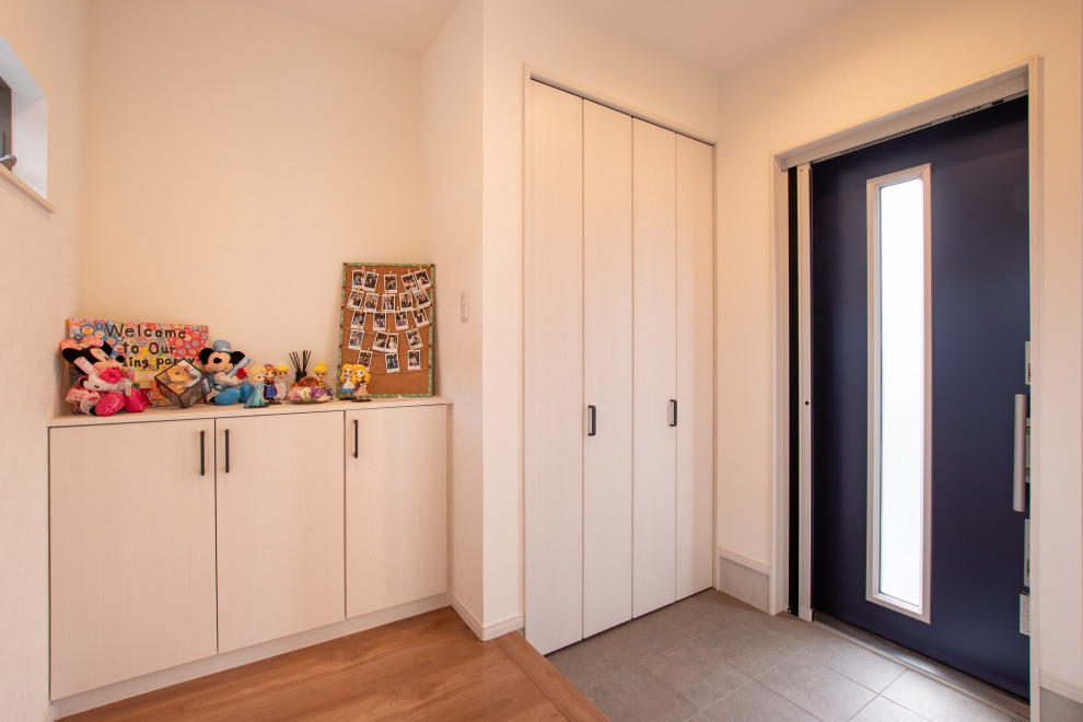 Foto de hall actual pequeño con paredes blancas, suelo de piedra caliza, puerta corredera, puerta azul y suelo marrón