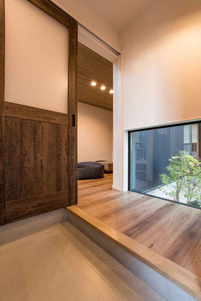 Foto de hall de estilo zen pequeño con paredes blancas, suelo de madera en tonos medios, puerta corredera, puerta de madera oscura, suelo beige, papel pintado y papel pintado