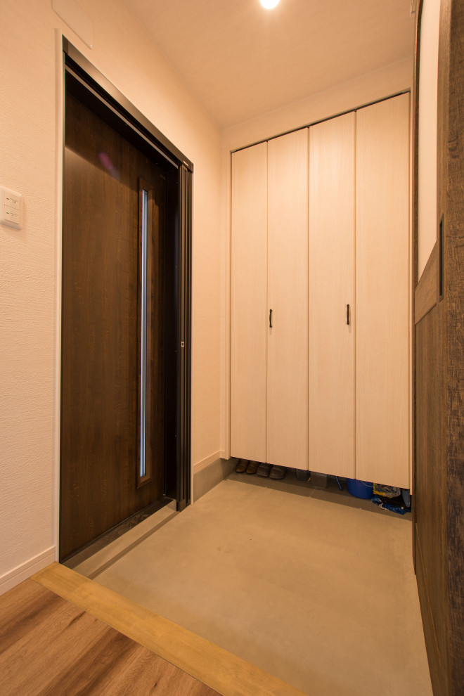Immagine di un piccolo corridoio etnico con pareti bianche, pavimento in cemento, una porta scorrevole, una porta in legno scuro, pavimento grigio, soffitto in carta da parati e carta da parati