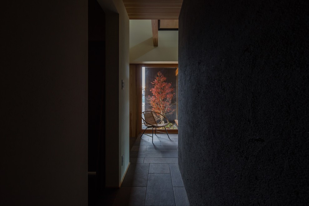 На фото: узкая прихожая среднего размера в восточном стиле с бежевыми стенами, паркетным полом среднего тона, раздвижной входной дверью, входной дверью из светлого дерева и бежевым полом