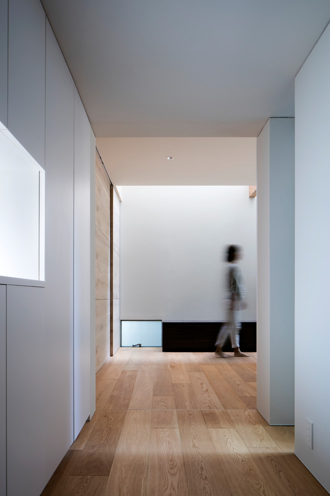 Idéer för små funkis hallar, med vita väggar, plywoodgolv, en dubbeldörr och en vit dörr