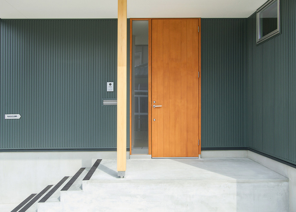 Exempel på en mellanstor modern entré, med gröna väggar, betonggolv, mellanmörk trädörr och grått golv