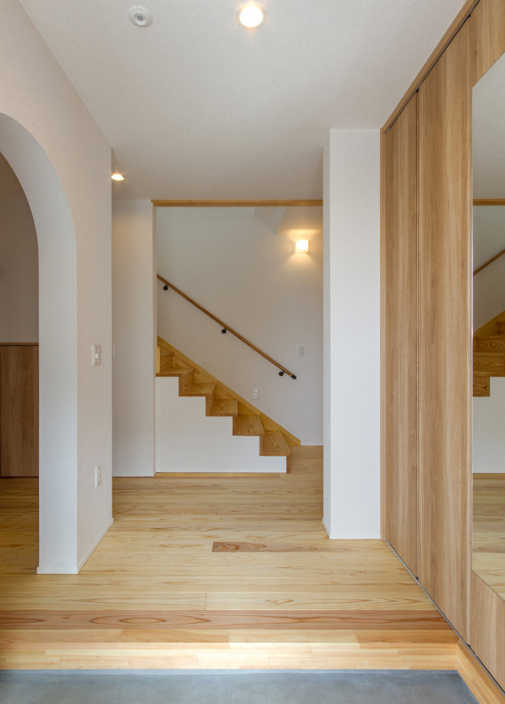 Ejemplo de entrada minimalista de tamaño medio con paredes blancas, suelo de madera clara, puerta simple, puerta de madera en tonos medios, suelo beige, papel pintado y papel pintado