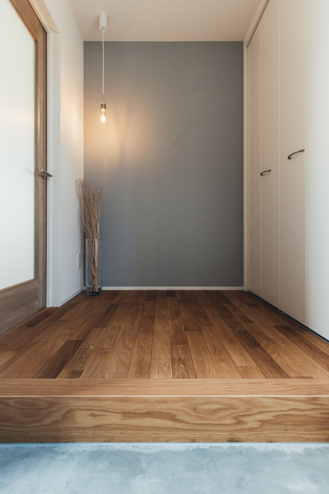 Ispirazione per un corridoio moderno di medie dimensioni con pareti grigie, pavimento in legno massello medio, una porta singola, una porta in legno bruno e pavimento marrone