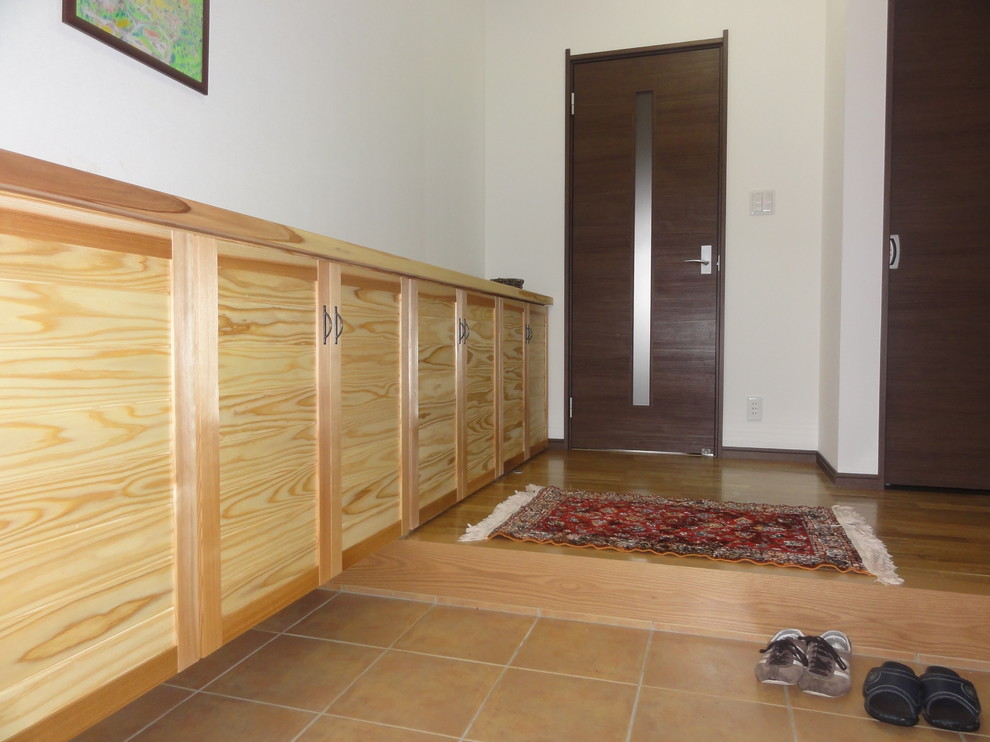 Ejemplo de hall campestre grande con paredes blancas, suelo de madera en tonos medios, puerta simple, puerta marrón y suelo marrón